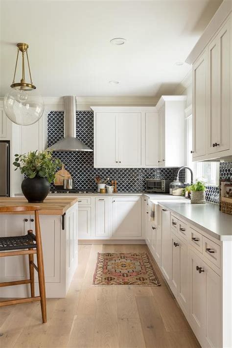 White modern kitchen cabinets offer black hardware along with gray backsplash, and dark wood floor. Black Backsplash Tiles with White Cabinets - Transitional ...