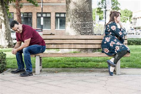 Unhappy Mixed Race Couple Sitting Facing Away From Each Other On Park