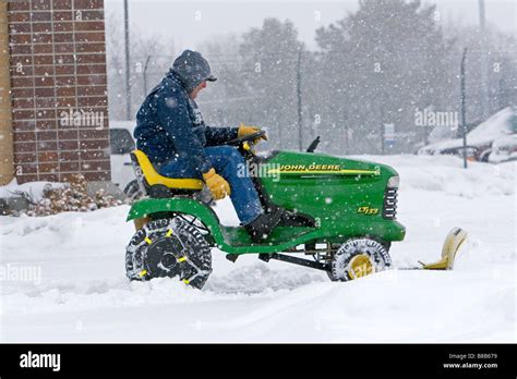 John Deere Riding Lawn Mower Fitted With A Snow Plow Removing Snow From