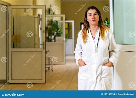 Female Doctor Standing In A Hospital Corridor Waiting For Patients To