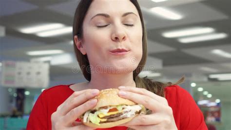 Hungry Girl Eating Hamburger On Food Court Woman Biting Cheeseburger At Fast Food Restaurant