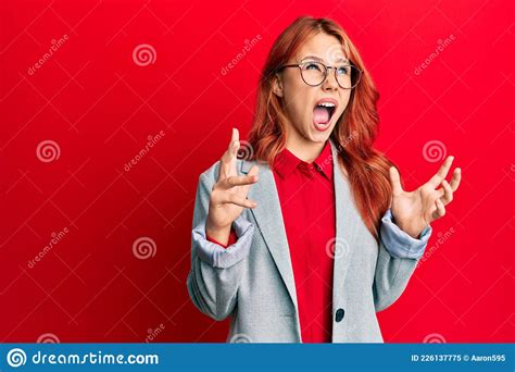 Young Redhead Woman Wearing Business Jacket And Glasses Crazy And Mad Shouting And Yelling With