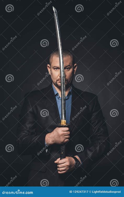 Mature Man In Suit Holding Japanese Katana Sword In Front Of His Face