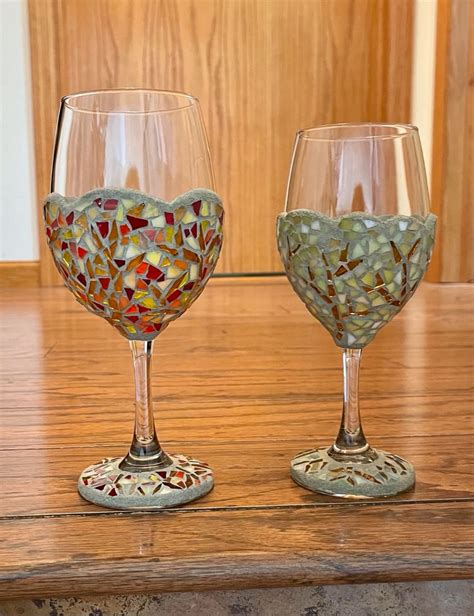 two wine glasses sitting on top of a wooden table covered in colorful glass mosaics