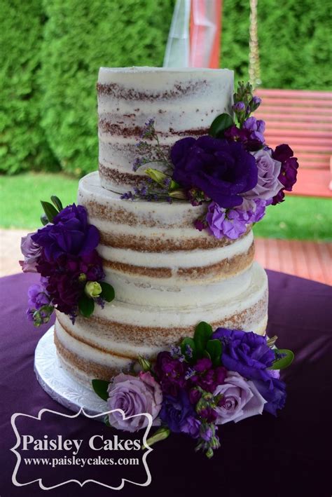 A Three Tiered Cake With Purple Flowers On Top
