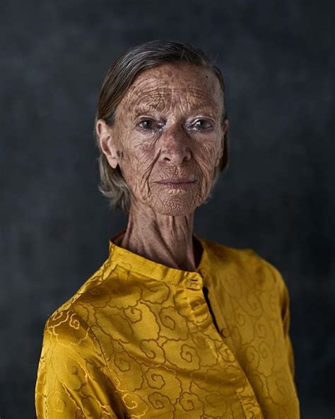 An Older Woman With Wrinkles On Her Face Posing For A Photo In Front Of A Dark Background