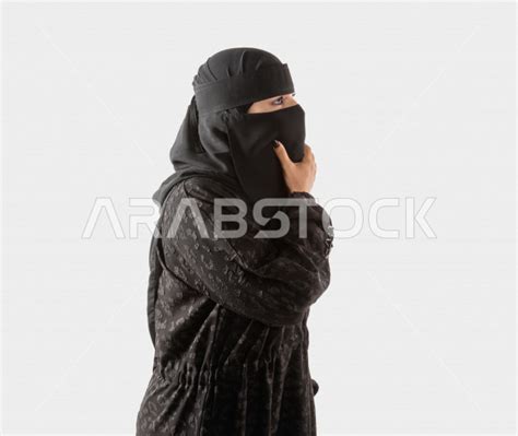 portrait of a veiled saudi arabian gulf woman wearing a black abaya gestures indicating