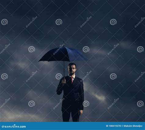 Businessman With Umbrella Standing Over Stormy Background Stock Photo