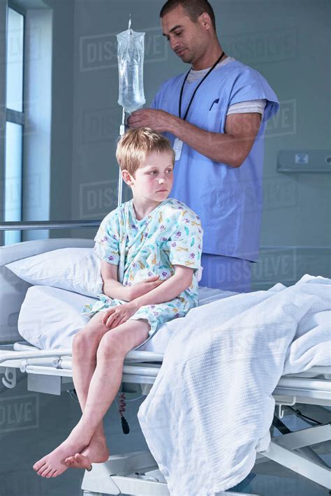 Male Nurse Adjusting Boy Patients Intravenous Drip In Hospital Children