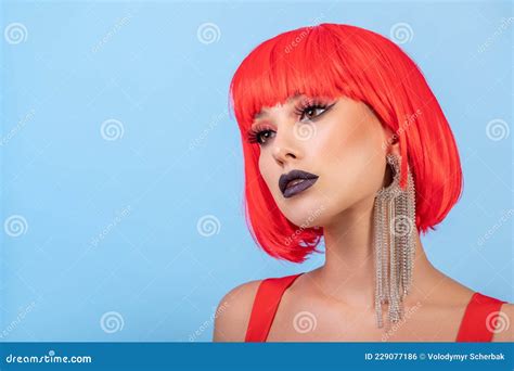 портрет красивой сексуальной женщины в красном парике на синем фоне Стоковое Фото изображение