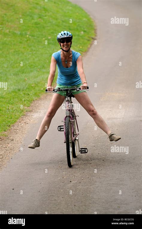 Woman Cyclist Freewheeling Downhill With Legs Outstretched On A Quiet
