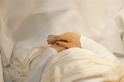A Woman Laying In Bed With Her Hand On The Pillow