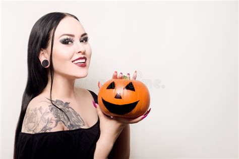 A Beautiful Brunette Holds A Pumpkin In Her Hands And Smiles Halloween