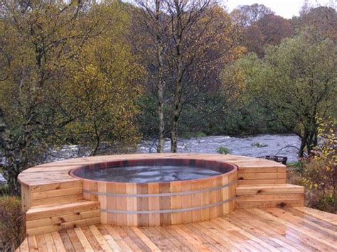 A Hot Tub Sitting On Top Of A Wooden Deck Next To A Forest Filled With