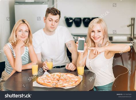 Attractive Blonde Caucasian Girl Enjoying Pizza With Friends In Kitchen