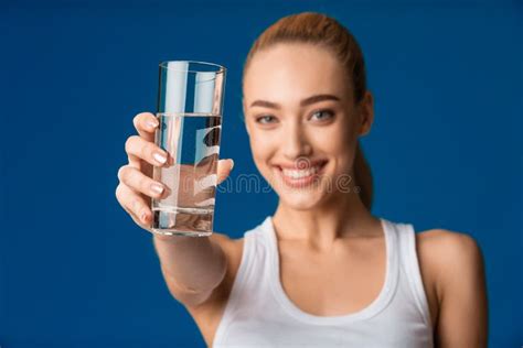 Girl Offering Glass Of Water To Camera Over Blue Background Stock Photo