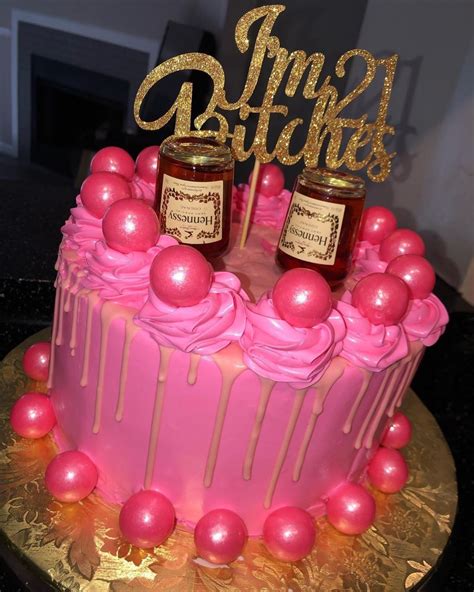 A Cake With Pink Icing And Two Jars On Top That Have Gold Glitter Letters