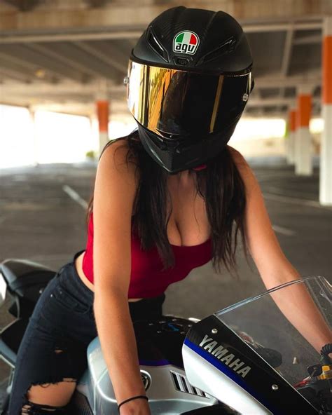 A Woman Sitting On Top Of A Motorcycle Wearing A Helmet And Holding