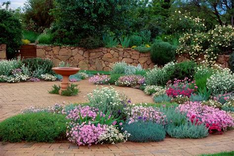 A Garden Filled With Lots Of Flowers Next To A Stone Wall Covered In