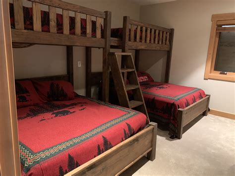 Two Bunk Beds In A Bedroom With Red Blankets And Wooden Ladders On Each Bed