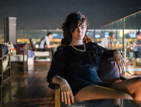 Edgy Woman Sitting Alone At Rooftop Bar At Night Del Colaborador De
