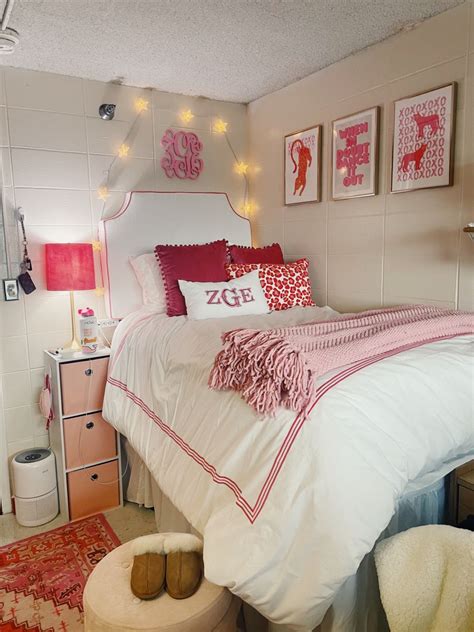 a white bed with pink and red pillows in a bedroom next to a rug on the floor
