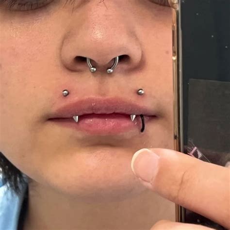 A Woman With Piercings On Her Nose Holding A Cell Phone