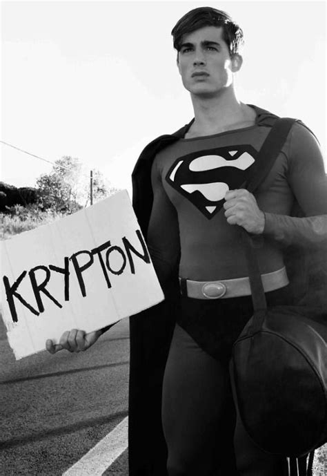 A Man Dressed As Superman Holding A Sign That Says Krypton On It