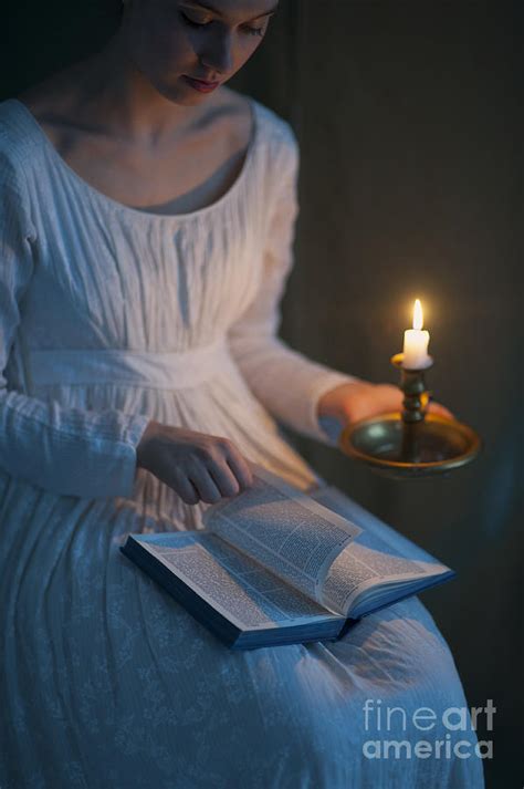 Woman In A Regency Period Dress Reading A Book By Candlelight