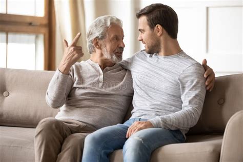 Happy Older Father And Son Having Pleasant Conversation At Home Stock