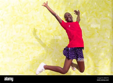 Smiling Young Woman Jumping In Air Over Yellow Background Happy African Woman Celebrating And
