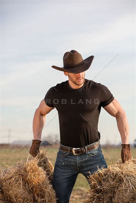 A Man Wearing A Cowboy Hat And Holding Two Bales Of Hay In His Hands