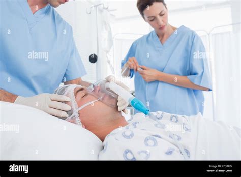Doctors Holding Oxygen Mask And Examining Intravenous Drip Stock Photo