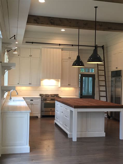 There are a variety of farmhouse style kitchen. beams pendants, shiplap, island, lights above the sink ...