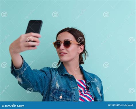 Portrait Of Young Girl Taking Selfie On Blue Background Stock Photo