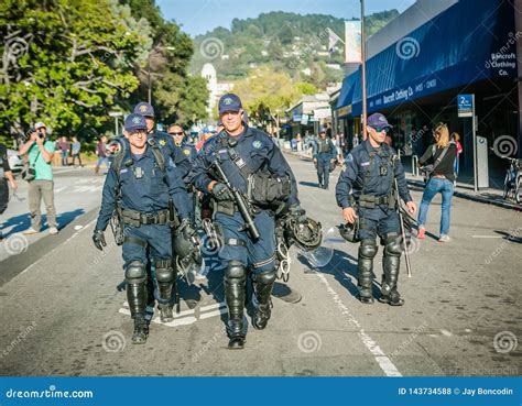 A Group Of Police Officers Walking Down The Street In Berkeley