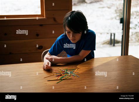 Boy Playing Pick Up Sticks At Table In Home Stock Photo Alamy