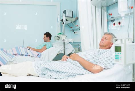 Two Male Patients Lying On Hospital Beds In A Hospital Ward Stock Photo