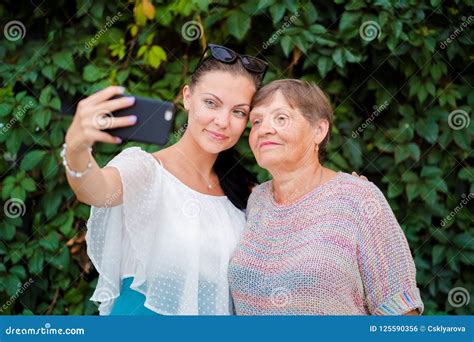 Pretty Old Granny And Her Granddaughter Doing Selfie Outdoor Fooling