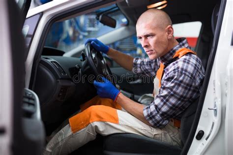Auto Mechanic Sitting In Broken Car And Listens To Engine Operation