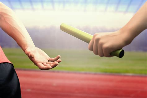 Athlete Passing A Baton To The Partner Against Race Track Church Of God