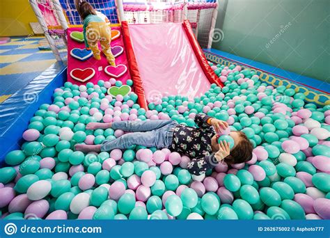 Happy Sisters Playing At Indoor Play Center Playground Girl Lying At Color Balls In Ball Pool