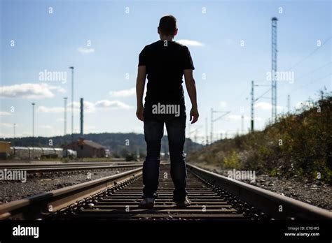 Silhouette of a man from behind standing on railway tracks Stock Photo ...
