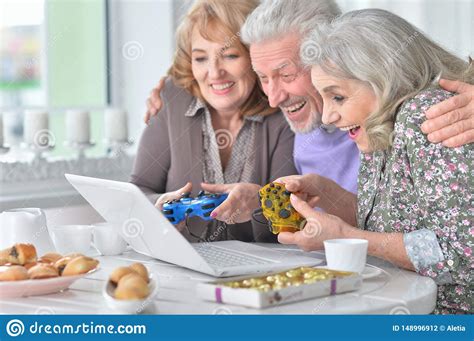 Senior People Playing Computer Game With Laptop While Drinking Tea