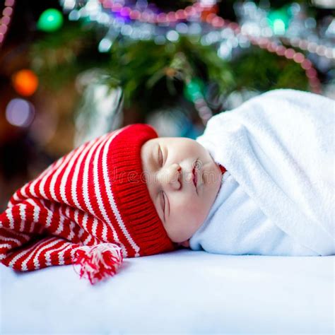 One Week Old Newborn Baby In Santa Hat Wrapped In Blanket Near