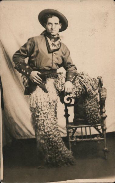 Man Dressed As A Cowboy Wearing Wooly Chaps And Holding A Pistol