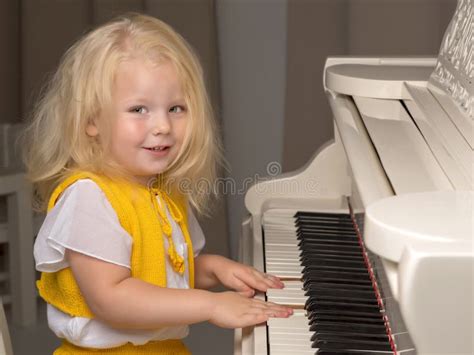 Beautiful Little Girl Is Playing On A White Grand Piano Stock Image