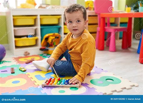 Adorable Caucasian Boy Playing Xylophone Sitting On Floor At