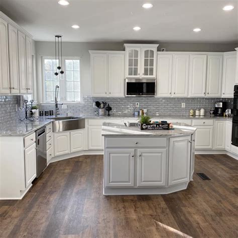 A Large Kitchen With White Cabinets And Wood Floors