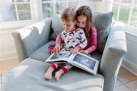 Little Brother Looking At A Photo Album With His Big Sister By